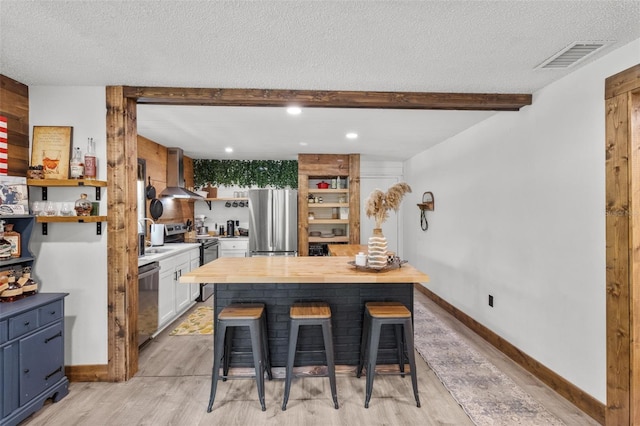 9821 113th St Unit 201, Seminole, FL 33772 - kitchen with appliances with stainless steel finishes, wall chimney range hood, light wood-style floors, butcher block countertops, and open shelves