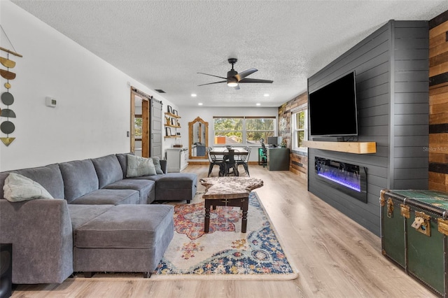 9821 113th St Unit 201, Seminole, FL 33772 - living room featuring ceiling fan, a textured ceiling, a glass covered fireplace, and wood finished floors