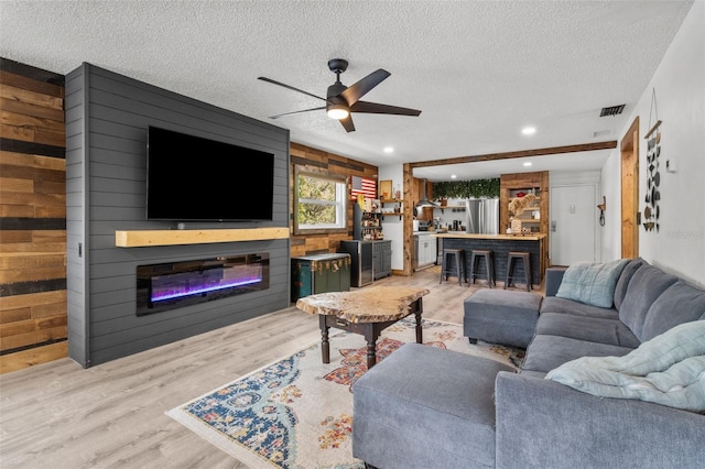 9821 113th St Unit 201, Seminole, FL 33772 - living area with a glass covered fireplace, wooden walls, wood finished floors, a ceiling fan, and a textured ceiling