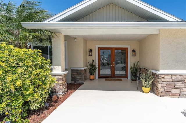 view of exterior entry with stone siding, stucco siding, and french doors