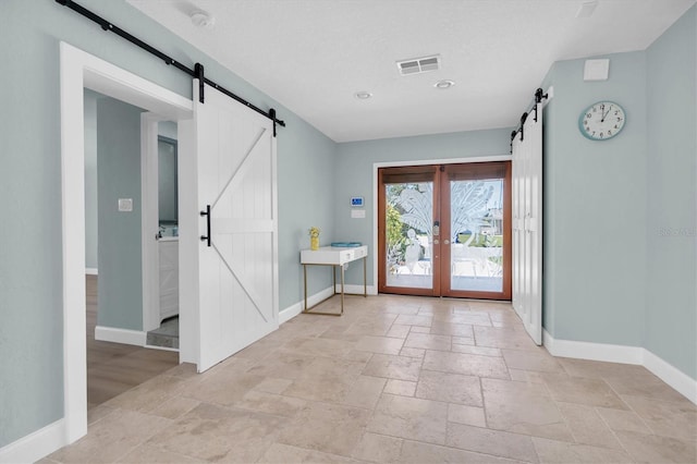 doorway featuring a barn door, stone tile flooring, baseboards, and recessed lighting