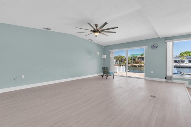 unfurnished room featuring baseboards, a water view, ceiling fan, wood finished floors, and lofted ceiling