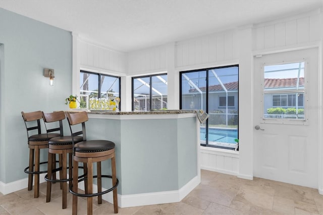 kitchen featuring baseboards, a breakfast bar area, and light stone finish floors