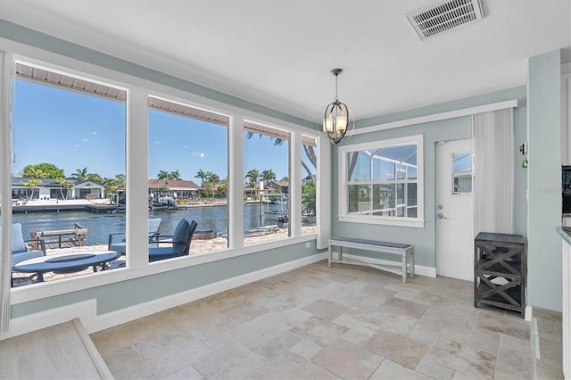 unfurnished dining area with a water view, a chandelier, light stone finish floors, and baseboards