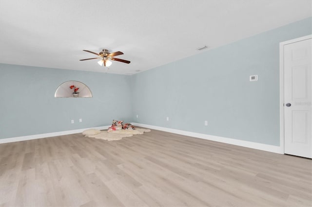 empty room featuring light wood-type flooring, a ceiling fan, and baseboards