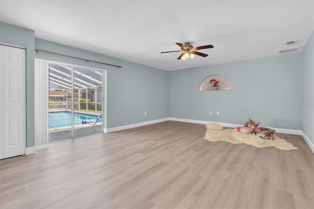 empty room featuring ceiling fan, baseboards, a sunroom, and light wood-style flooring