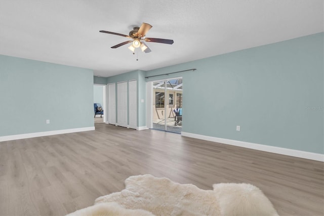 unfurnished living room with ceiling fan, wood finished floors, and baseboards
