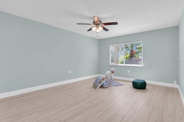 workout area featuring ceiling fan, baseboards, and light wood-type flooring