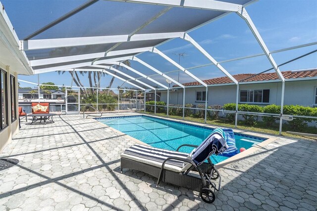 swimming pool featuring glass enclosure and a patio