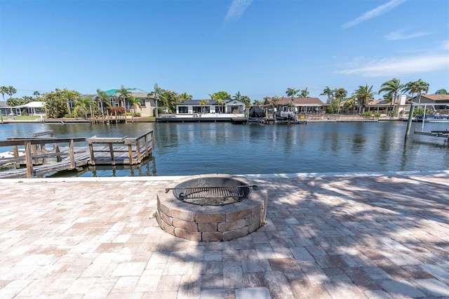 dock with an outdoor fire pit, a water view, and a residential view