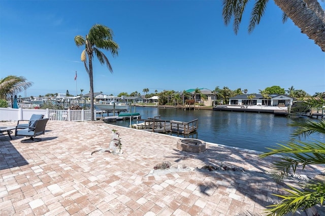 dock area with a water view, an outdoor fire pit, fence, and a patio area