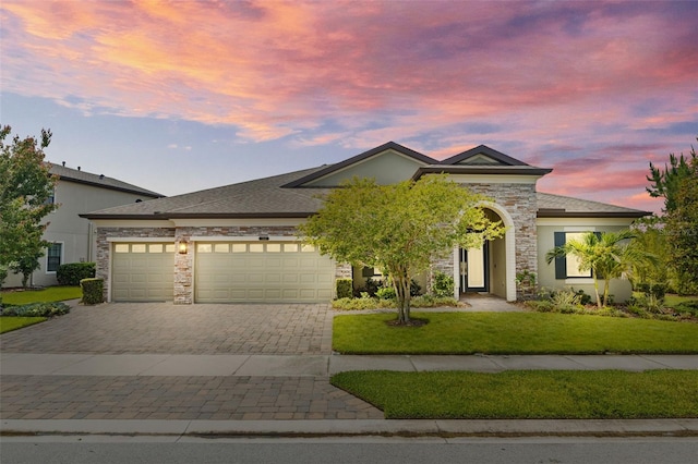 21642 Emory Oak Pl, Land O Lakes, FL 34637 - view of front of home with decorative driveway, a garage, a lawn, stone siding, and stucco siding