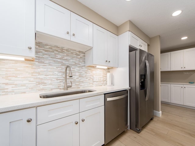 kitchen with stainless steel appliances, a sink, white cabinets, recessed lighting, and decorative backsplash