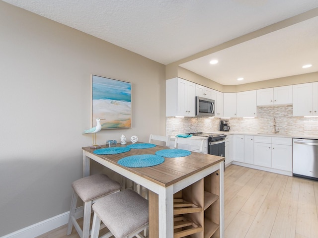kitchen with dishwashing machine, stainless steel microwave, a sink, tasteful backsplash, and recessed lighting