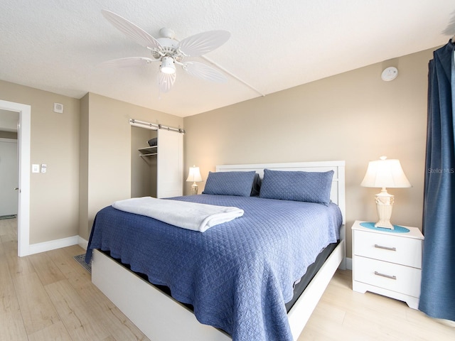 bedroom with light wood-style floors, baseboards, a ceiling fan, and a closet
