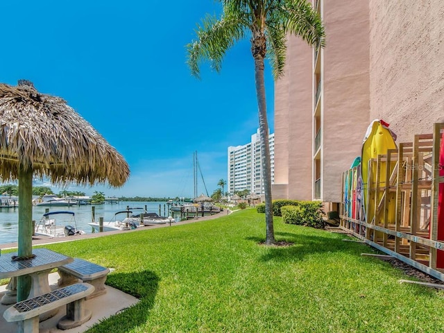 view of home's community with a dock, a lawn, and a water view