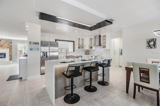 5744 150th Ave N, Clearwater, FL 33760 - kitchen with stainless steel appliances, light countertops, wall chimney exhaust hood, white cabinetry, and a breakfast bar