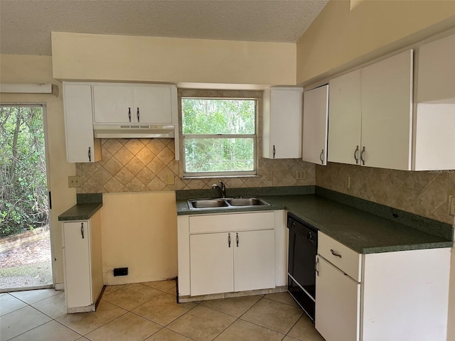 kitchen with a sink, dishwasher, under cabinet range hood, dark countertops, and a textured ceiling