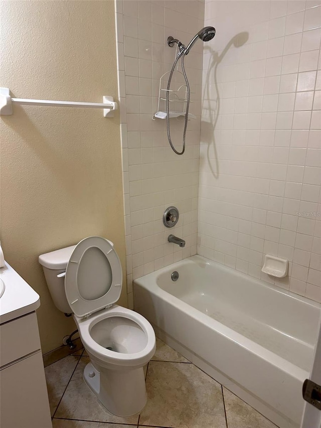 bathroom with toilet, tile patterned floors, washtub / shower combination, vanity, and a textured wall