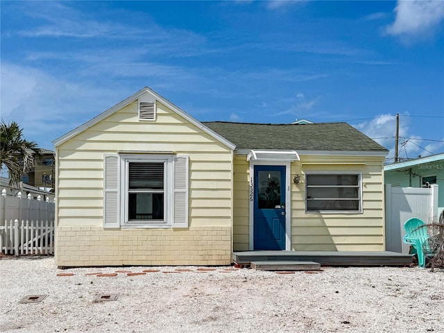13326 1st St E, Madeira Beach, FL 33708 - view of front facade with fence, brick siding, and a shingled roof