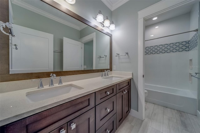 bathroom featuring crown molding, double vanity, toilet, washtub / shower combination, and baseboards
