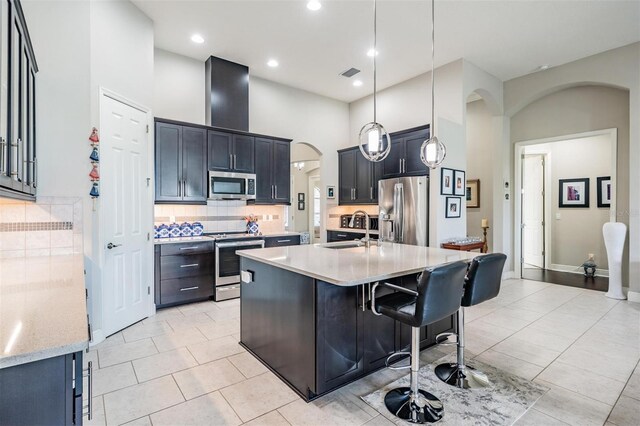 32242 Summerglade Dr, Wesley Chapel, FL 33545 - kitchen featuring stainless steel appliances, a sink, arched walkways, backsplash, and light tile patterned flooring