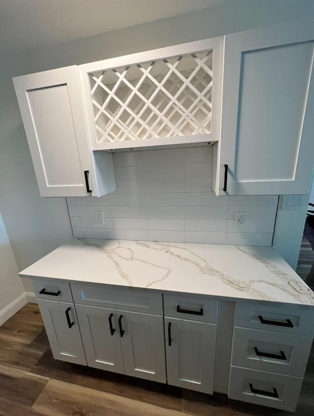 2424 W Tampa Bay Blvd Unit 203, Tampa, FL 33607 - kitchen featuring backsplash, dark wood-type flooring, light stone counters, baseboards, and white cabinetry