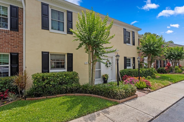 multi unit property with stucco siding and a front yard