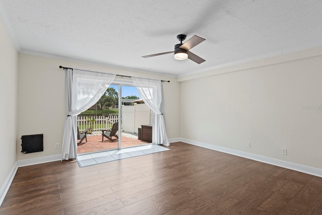 empty room featuring crown molding, dark wood-style flooring, a ceiling fan, a textured ceiling, and baseboards