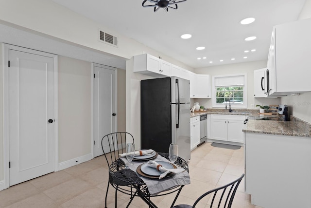 kitchen with appliances with stainless steel finishes, white cabinets, recessed lighting, a sink, and light tile patterned flooring