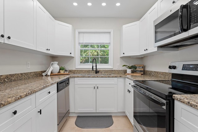 kitchen with appliances with stainless steel finishes, a sink, recessed lighting, white cabinetry, and light tile patterned floors