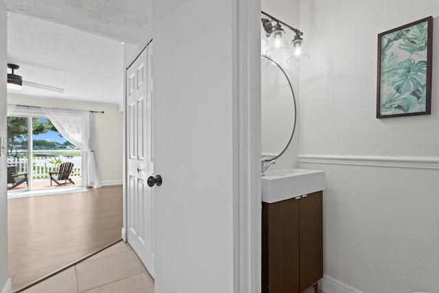 bathroom featuring a textured ceiling, vanity, tile patterned floors, and baseboards