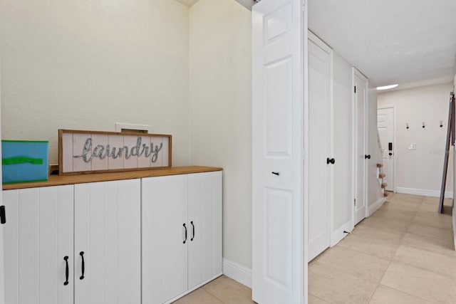 hallway featuring light tile patterned floors and baseboards