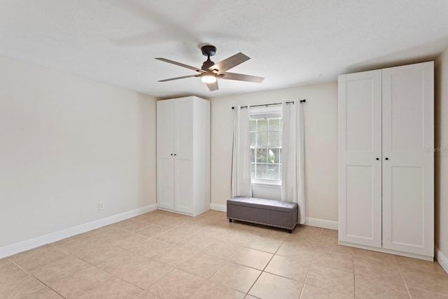 unfurnished bedroom featuring light tile patterned flooring, baseboards, and a ceiling fan