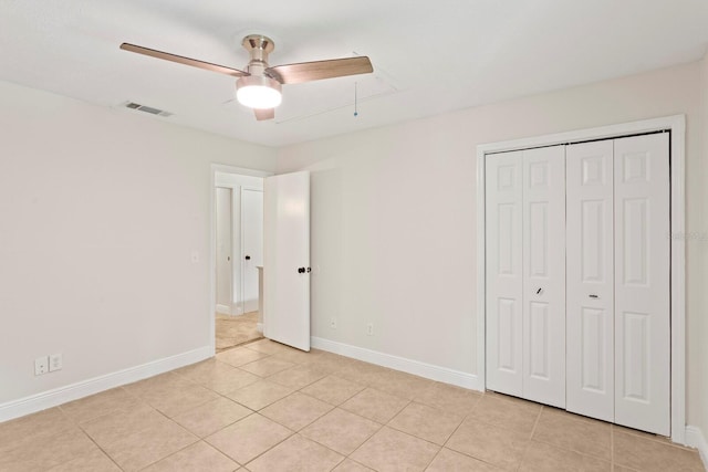 unfurnished bedroom with light tile patterned floors, baseboards, a closet, and attic access
