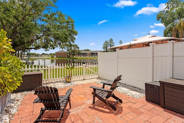 view of patio / terrace featuring a water view and fence