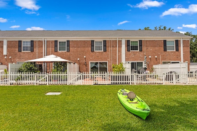back of property with a gazebo, a yard, and brick siding