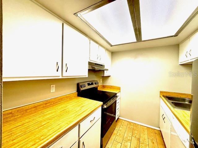296 Lewfield Cir, Winter Park, FL 32792 - kitchen featuring stainless steel electric range, under cabinet range hood, light wood-style flooring, white cabinetry, and light countertops