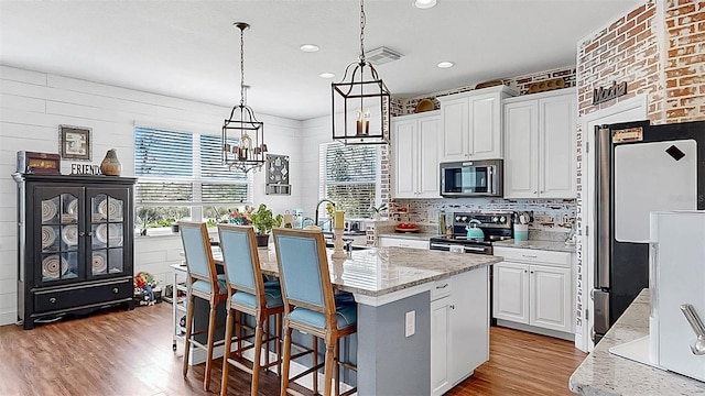 5040 Inshore Landing Dr, Apollo Beach, FL 33572 - kitchen with stainless steel appliances, light wood-style floors, an island with sink, white cabinetry, and recessed lighting