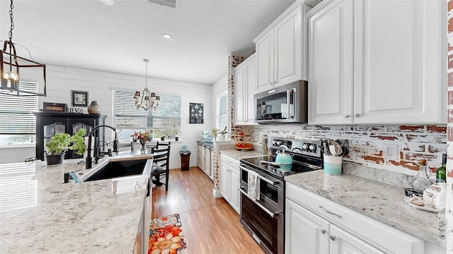 5040 Inshore Landing Dr, Apollo Beach, FL 33572 - kitchen featuring appliances with stainless steel finishes, a chandelier, a sink, light wood-style flooring, and white cabinetry
