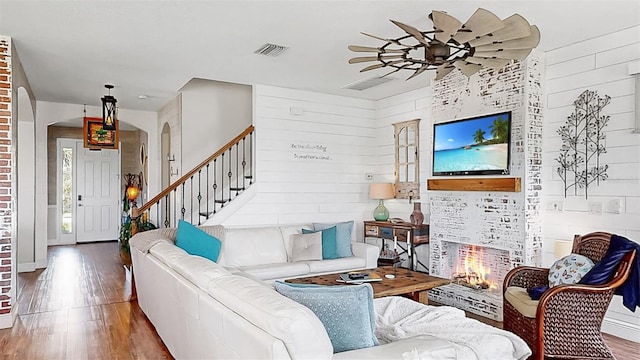 5040 Inshore Landing Dr, Apollo Beach, FL 33572 - living area featuring wood finished floors, arched walkways, ceiling fan, a warm lit fireplace, and stairway