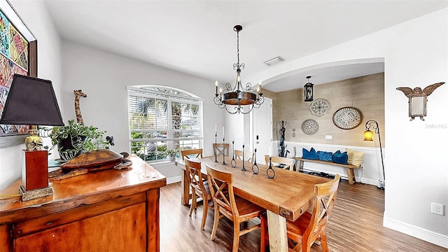 5040 Inshore Landing Dr, Apollo Beach, FL 33572 - dining area featuring light wood-style flooring, a chandelier, baseboards, arched walkways, and vaulted ceiling