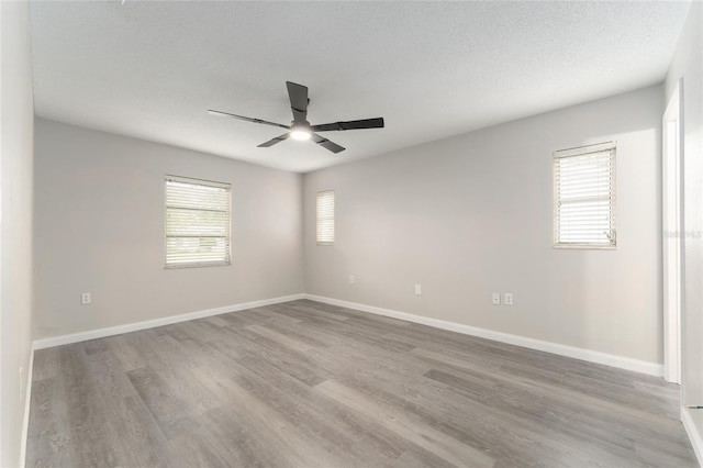 unfurnished room featuring a ceiling fan, wood finished floors, and healthy amount of natural light