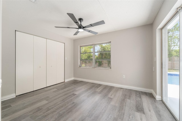 unfurnished bedroom featuring light wood-type flooring, access to outside, a closet, baseboards, and ceiling fan