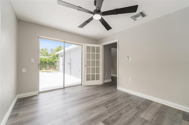 empty room with wood finished floors, a ceiling fan, and baseboards