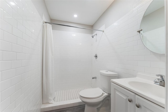 bathroom with tile walls, a tile shower, toilet, and vanity