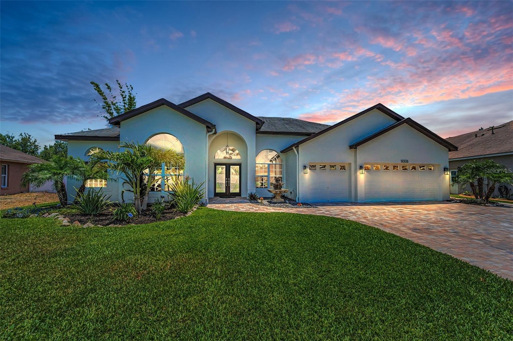 9208 Brindlewood Dr, Odessa, FL 33556 - ranch-style home featuring french doors, stucco siding, driveway, a lawn, and a garage