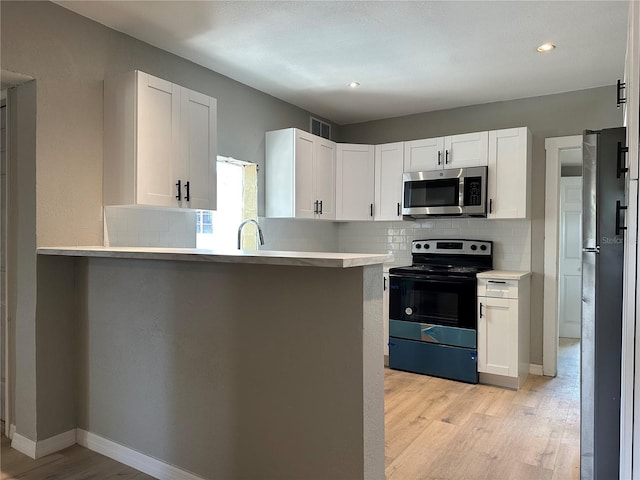 1536 S Martin Luther King Jr Ave, Clearwater, FL 33756 - kitchen featuring appliances with stainless steel finishes, tasteful backsplash, light wood finished floors, white cabinetry, and recessed lighting