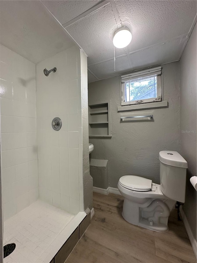 1536 S Martin Luther King Jr Ave, Clearwater, FL 33756 - bathroom with toilet, wood finished floors, tiled shower, baseboards, and a textured wall
