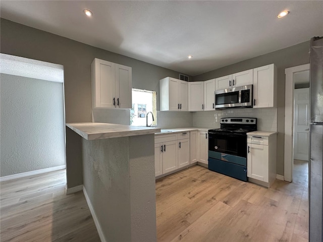 1536 S Martin Luther King Jr Ave, Clearwater, FL 33756 - kitchen with stainless steel microwave, electric range, white cabinets, light wood-type flooring, and baseboards
